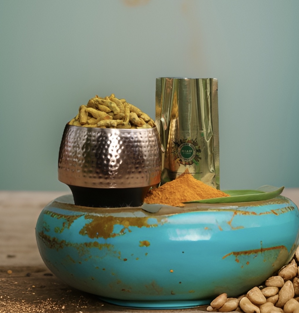 A bowl of whole dried turmeric fingers beside a small heap of turmeric powder and a Miller Stores pouch